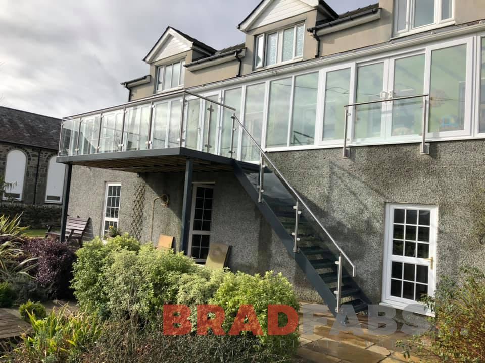 Bespoke balcony with staircase by Bradfabs Ltd, stainless steel and glass balustrade, composite decked flooring, durbar treads, mild steel and galvanised, powder coated 