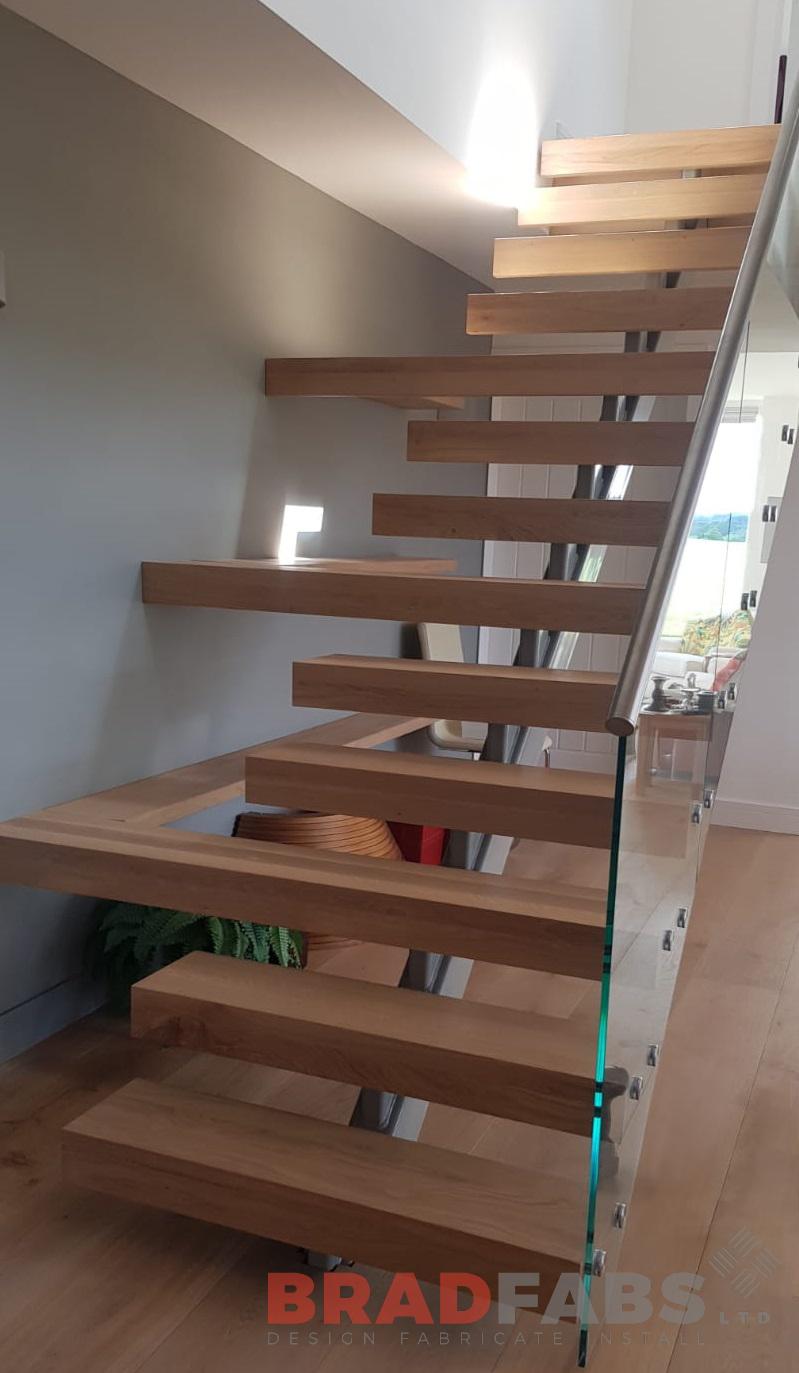 Beautiful modern staircase with oversized oak treads and infinity glass balustrade and stainless steel handrail by Bradfabs 